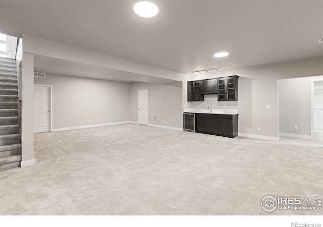 basement featuring carpet flooring, sink, and track lighting