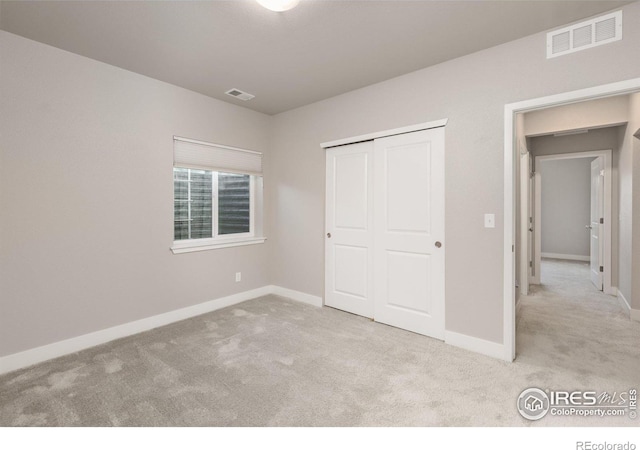 unfurnished bedroom with light colored carpet and a closet