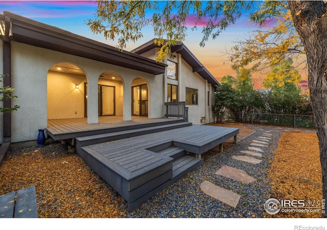 back house at dusk featuring a deck