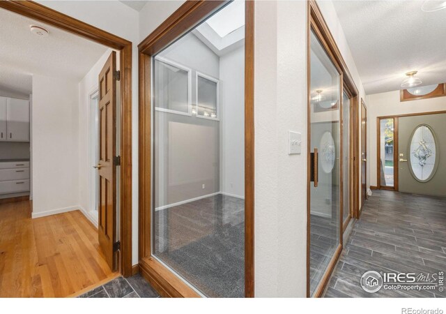 hallway featuring a skylight, hardwood / wood-style floors, and a textured ceiling