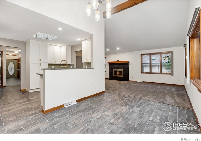 kitchen with kitchen peninsula, dark hardwood / wood-style flooring, white cabinetry, and lofted ceiling