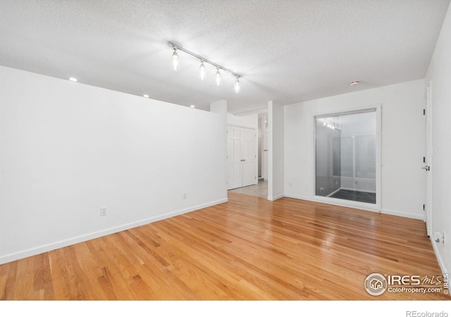 spare room with light wood-type flooring and a textured ceiling