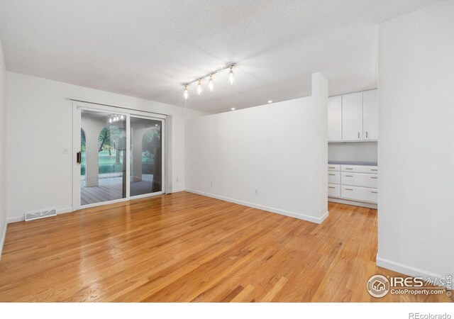 spare room featuring a textured ceiling and light wood-type flooring