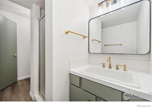 bathroom with backsplash, sink, an enclosed shower, and hardwood / wood-style flooring