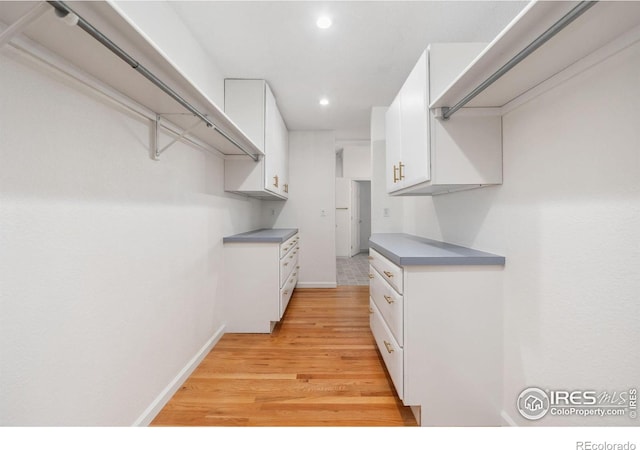 walk in closet with light hardwood / wood-style floors