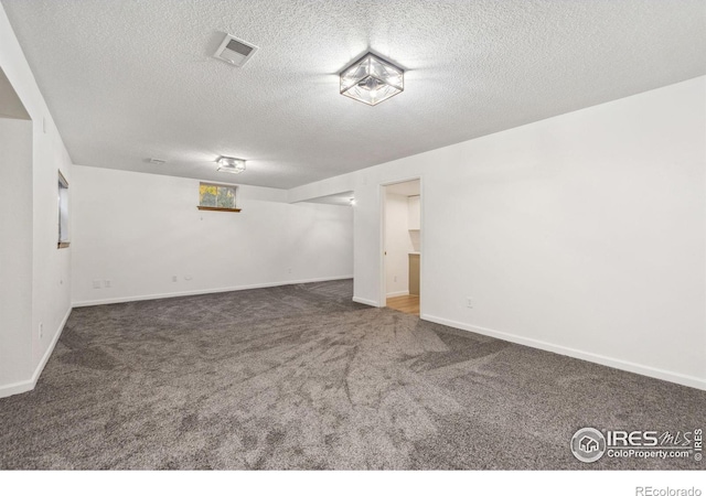 basement featuring dark colored carpet and a textured ceiling