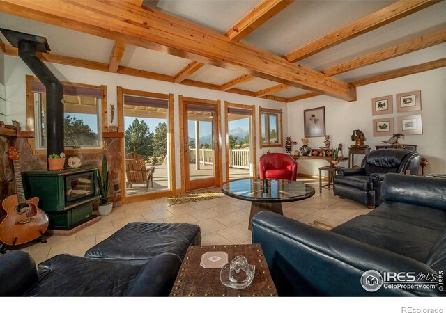 living room with light tile patterned floors, a wood stove, and beamed ceiling