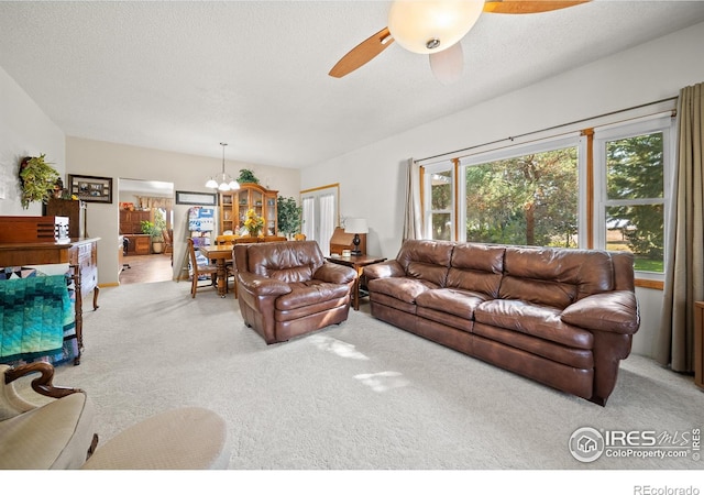 living room with carpet, a textured ceiling, and ceiling fan with notable chandelier