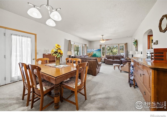 dining space with light carpet, a textured ceiling, and ceiling fan with notable chandelier