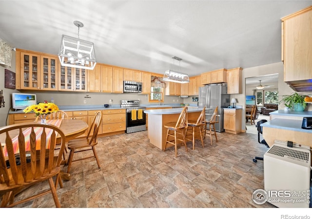 kitchen featuring sink, a center island, stainless steel appliances, pendant lighting, and a breakfast bar area