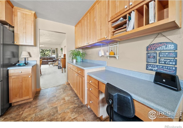 kitchen featuring built in desk, light brown cabinets, a textured ceiling, and fridge