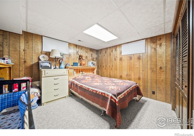 bedroom with wood walls, a paneled ceiling, and carpet