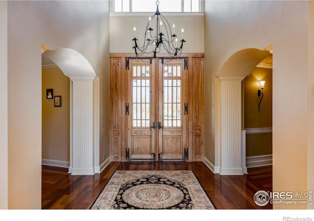 entrance foyer with french doors, ornate columns, crown molding, and dark wood-type flooring