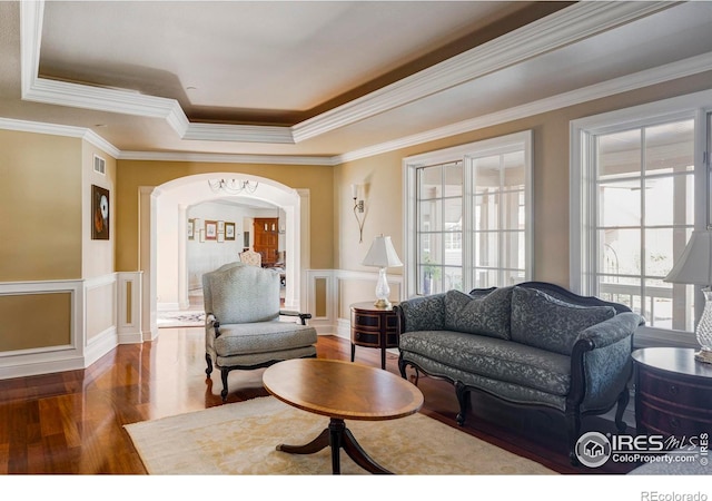 living room with ornamental molding, a tray ceiling, and dark hardwood / wood-style floors