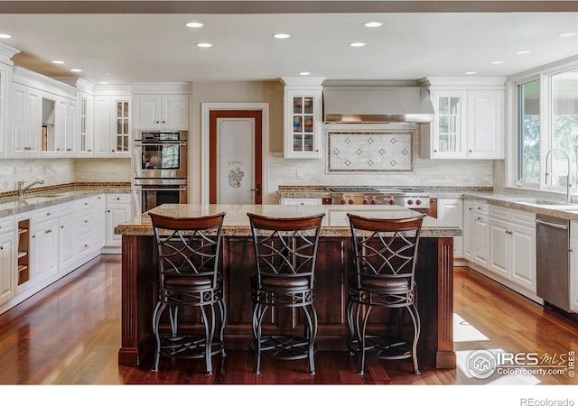 kitchen featuring wall chimney range hood, dark hardwood / wood-style floors, a center island, and white cabinetry