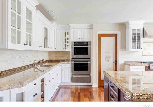 kitchen featuring tasteful backsplash, appliances with stainless steel finishes, white cabinetry, dark wood-type flooring, and sink