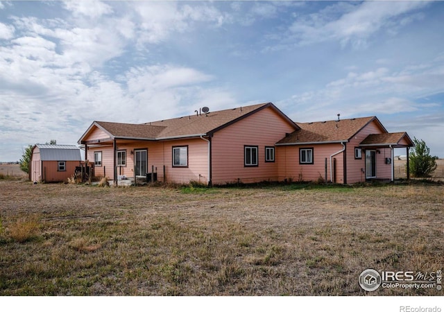 back of house featuring a storage unit