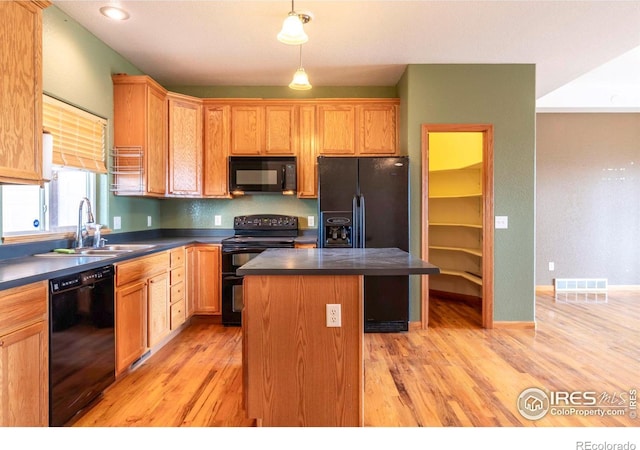 kitchen with black appliances, sink, a center island, hanging light fixtures, and light hardwood / wood-style flooring