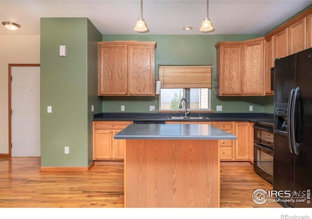 kitchen with black appliances, sink, light wood-type flooring, a center island, and decorative light fixtures