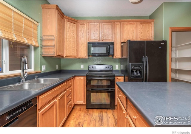 kitchen featuring black appliances, sink, and light wood-type flooring