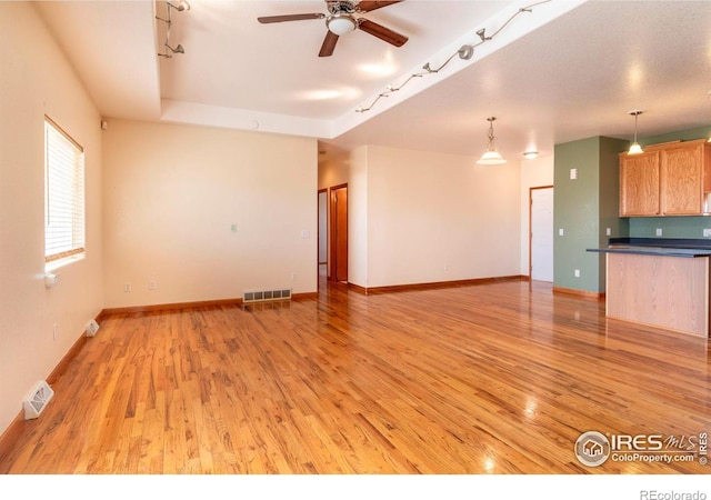 unfurnished living room with ceiling fan, light wood-type flooring, and rail lighting