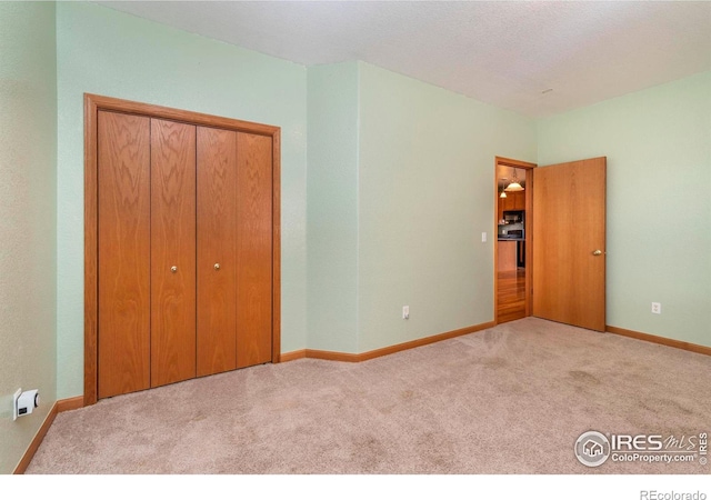 unfurnished bedroom featuring light carpet, a textured ceiling, and a closet