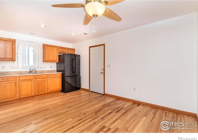 kitchen with sink, ceiling fan, light hardwood / wood-style floors, and black fridge