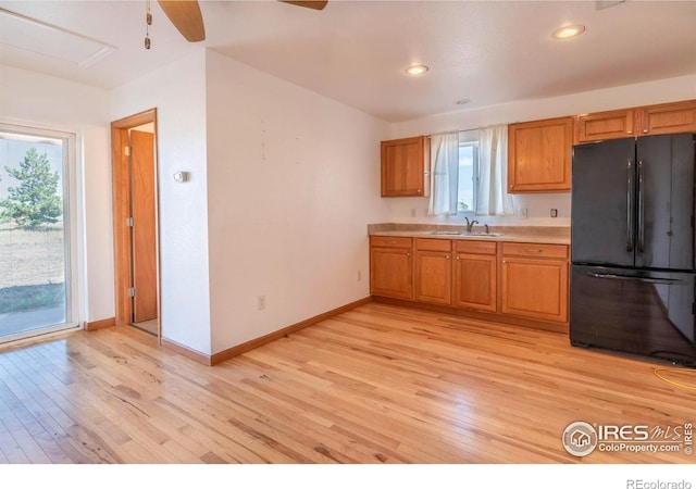 kitchen with light hardwood / wood-style flooring, sink, black fridge, and ceiling fan