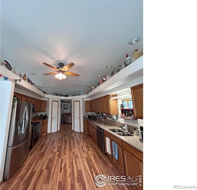 kitchen with light countertops, brown cabinets, appliances with stainless steel finishes, light wood-style floors, and a sink