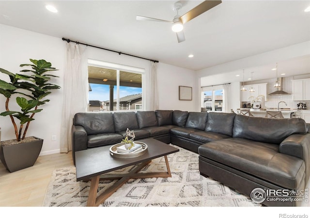 living room featuring sink, ceiling fan, and light hardwood / wood-style flooring