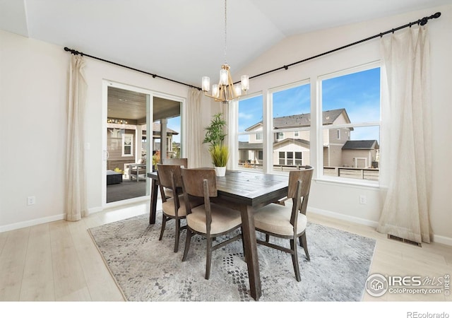 dining room with light hardwood / wood-style floors, a notable chandelier, and vaulted ceiling