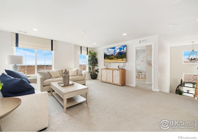 carpeted living room with a water view and a chandelier