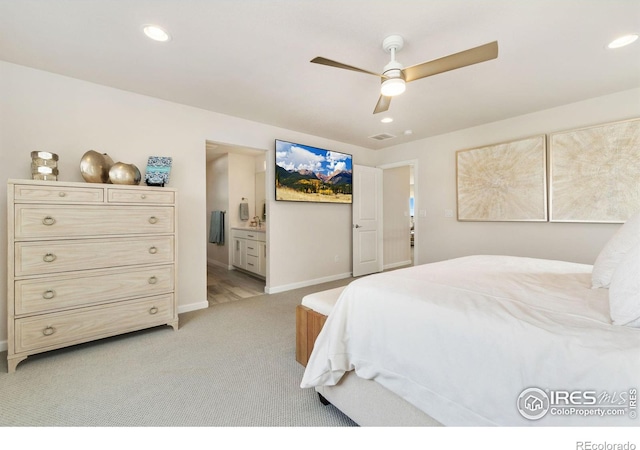 bedroom with ensuite bath, light colored carpet, and ceiling fan