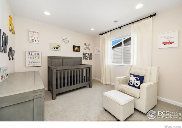 carpeted bedroom featuring a nursery area