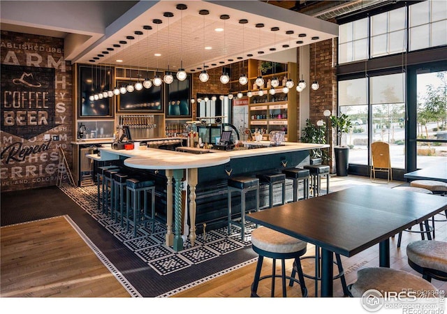 bar with a towering ceiling and hardwood / wood-style floors