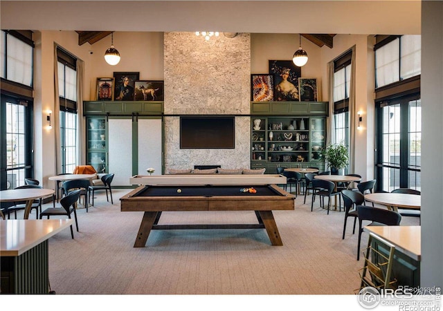 recreation room featuring beamed ceiling, carpet flooring, and a high ceiling