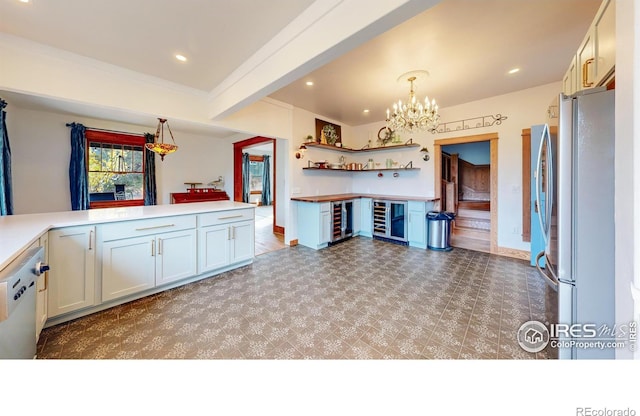 kitchen with stainless steel refrigerator, dishwasher, hanging light fixtures, beverage cooler, and white cabinets