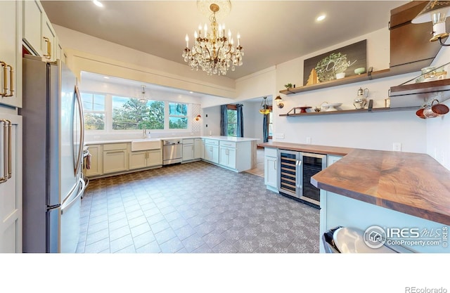 kitchen with butcher block counters, an inviting chandelier, wine cooler, decorative light fixtures, and appliances with stainless steel finishes