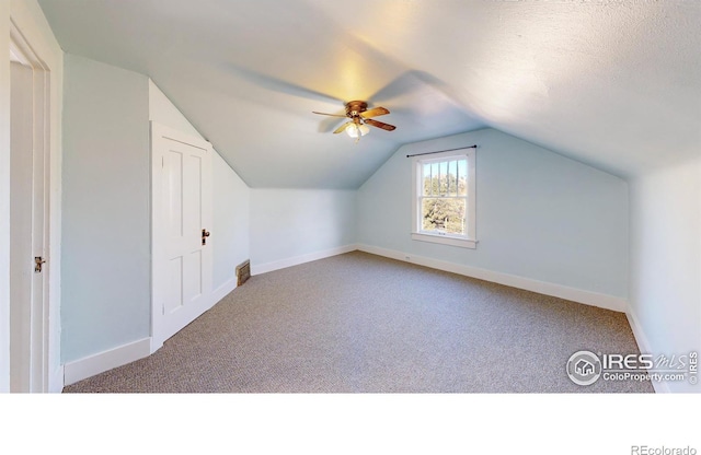 bonus room featuring a textured ceiling, light colored carpet, vaulted ceiling, and ceiling fan