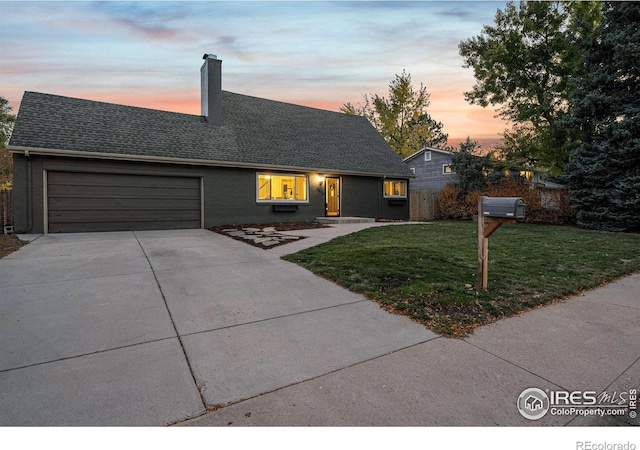 view of front of home with a garage and a lawn