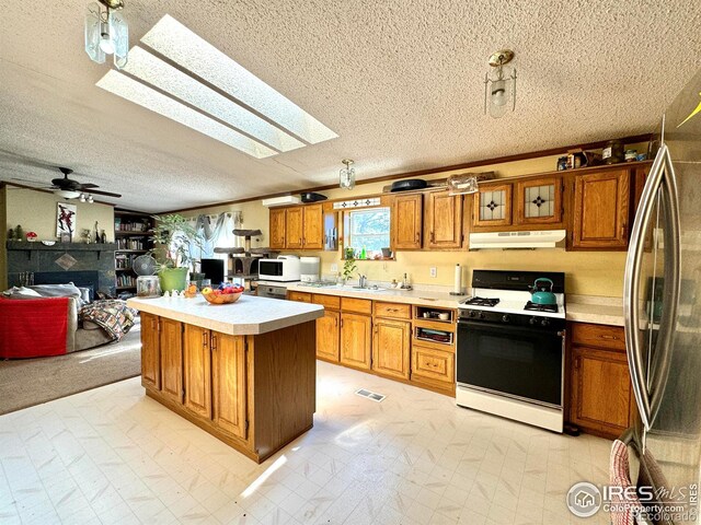 kitchen with a skylight, ceiling fan, sink, white appliances, and a kitchen island