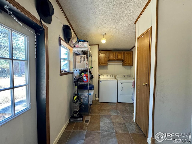 washroom with washer and dryer, a textured ceiling, and cabinets