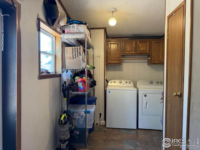 clothes washing area with washer and clothes dryer, cabinets, and a textured ceiling