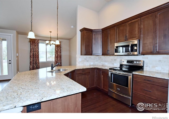 kitchen with sink, hanging light fixtures, stainless steel appliances, dark wood-type flooring, and decorative backsplash