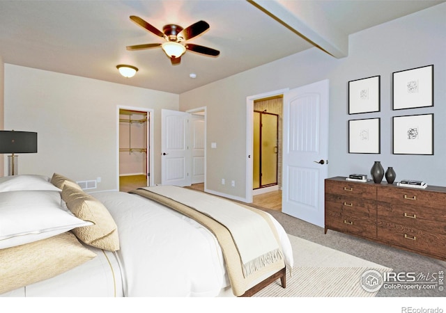 bedroom featuring a spacious closet, a closet, ceiling fan, beamed ceiling, and light colored carpet