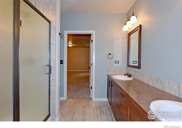 bathroom featuring a shower with door and vanity