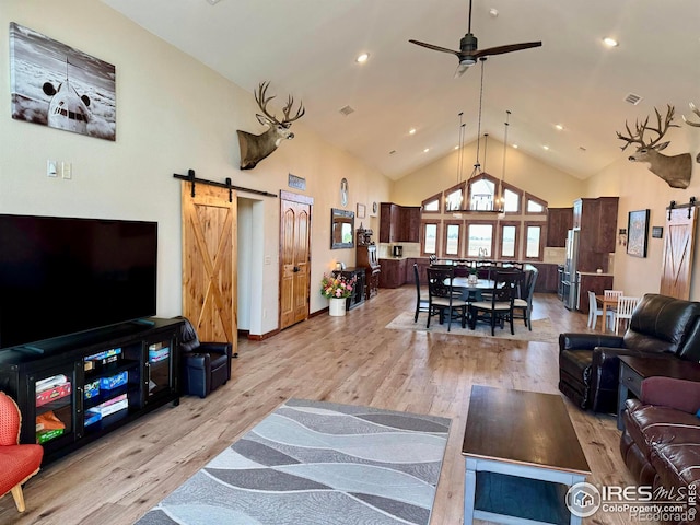 living room with a barn door, high vaulted ceiling, light hardwood / wood-style floors, and ceiling fan