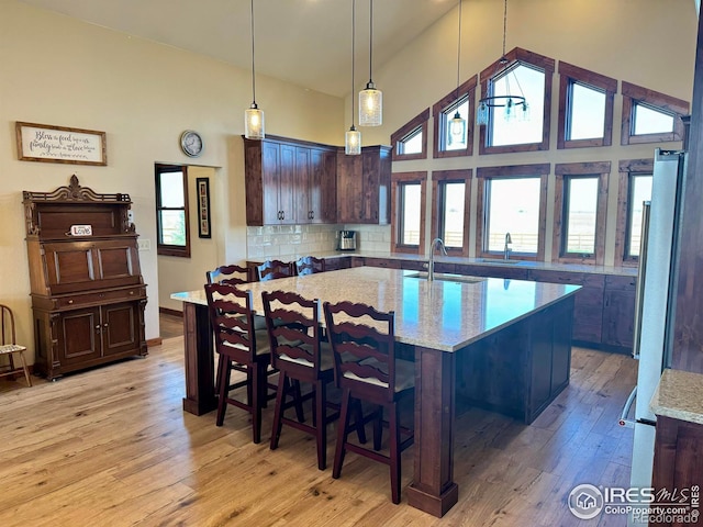 kitchen featuring light stone counters, light hardwood / wood-style floors, and a kitchen island with sink