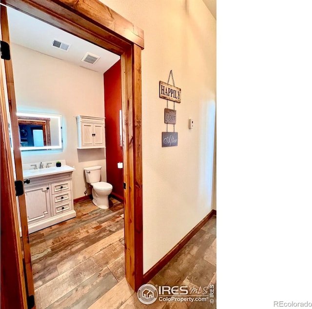 bathroom with vanity, toilet, and wood-type flooring