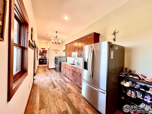 kitchen with light hardwood / wood-style flooring, stainless steel fridge, a healthy amount of sunlight, and sink